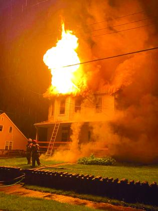 Flames shoot from the top of the Pettit home, 503 Maple Ave., Falmouth, in the early hours of April 30. Resident Bob Pettit, a retired firefighter and city councilman, said smoke detectors woke him and his wife, saving their lives. Photo by Kelly Braa.