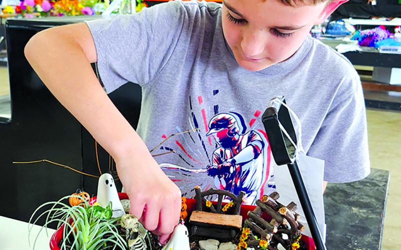 Kaleb Dunn, 8, of Foster, makes adjustments to his spooky fairy garden entry.