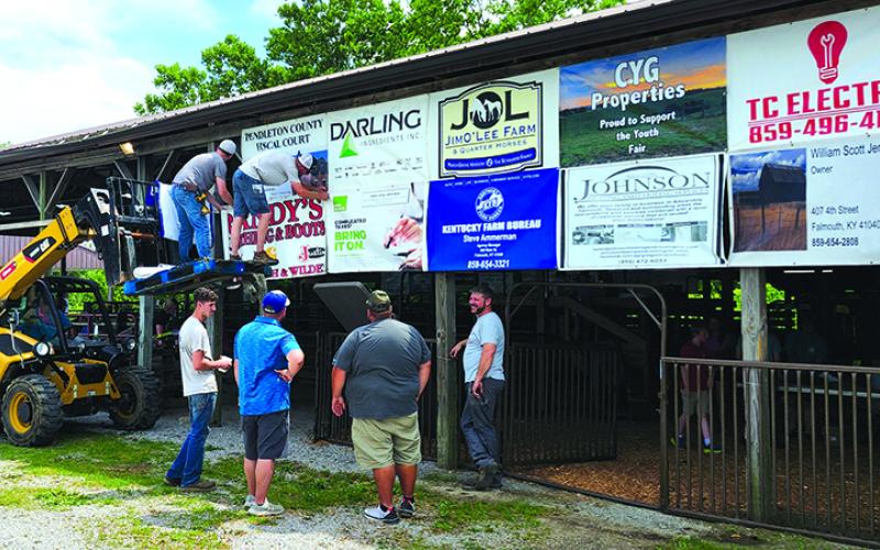 Pendleton County Youth Fair volunteers hang signs Sunday during fair setup.