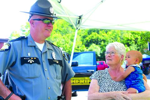 KSP Trooper David Jones talks with Juanita Hughes, holding  Myles, as her granddaughter takes pictures and her other grandson takes advantage of the fun.