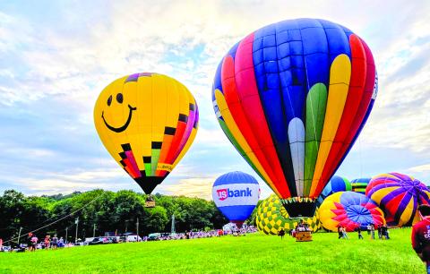 Two tethered balloons offer rides while the grounded balloons begin to inflate.